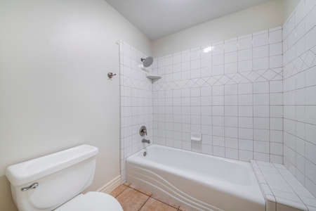 Interior of a bathroom with toilet bowl and alcove bathtub shower combo with tilesの写真素材