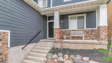 Pano Stairs going up the porch of home with gray front door and window at the facade