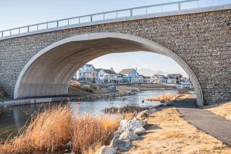 Arched bridge with gabion walls over a trail beside the lake