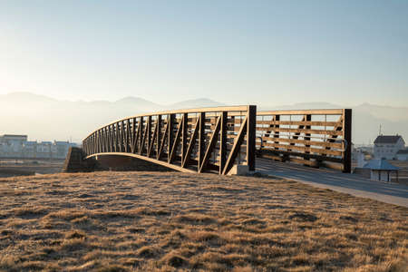 Curved bridge with metal beams and wooden railings with banister