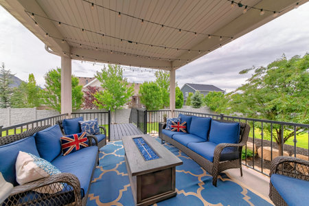 Cozy outdoor deck with fire pit table and woven sofas with blue cushionsの写真素材