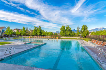 Large public pool surrounded by lounge chairs and wire fence at Daybreak, Utahの写真素材