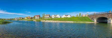 Panoramic view of Oquirrh Lake with grassy shore and stone bridge on the leftの写真素材