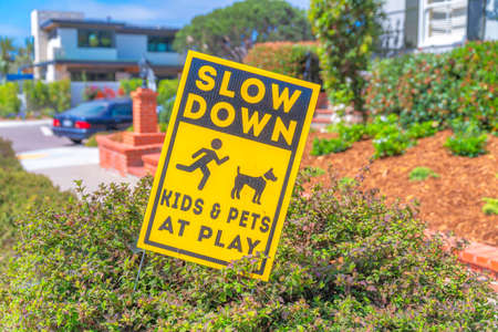 Slanted yellow signage on top of a bush at La Jolla, San Diego, California