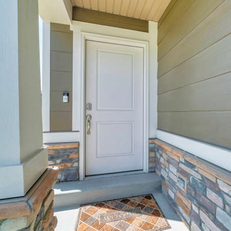 Square Home entrance exterior with white door and doormat