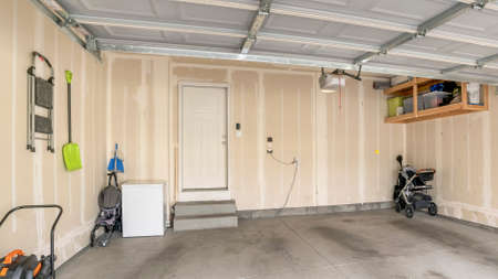 Panorama Garage interior with wall filler marks and white fire door. Garage with automatic door and...