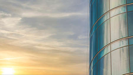 Panorama Puffy clouds at sunset Curved building exterior with glass curtain wall against the cloの写真素材