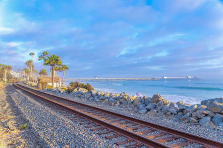 Rusty train tracks with a view of the ocean and pier at San Clemente, Californiaの写真素材