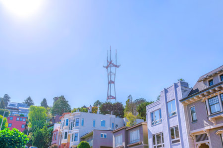 Sun over the residential area near the Sutro Tower in San Francisco, CA. There are sloped houses at the front below the Sutro Tower against the clear sky background.の写真素材