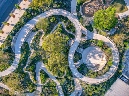 Aerial view of a park with small amphitheater and spiral pathway near the highway at Austin, Texas. There is a sidewalk on the top left corner with plants beside the park with plants and trees.の写真素材
