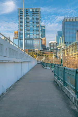 Walkway along the Colorado River in Austin Texas overlooking modern buildings. the paved walkway for visitors and people to enjoy a walk have safety railings.の写真素材