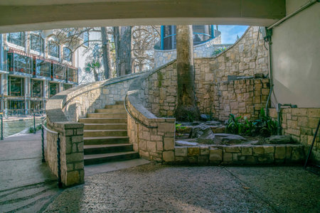View from under a bridge of an outdoor staircase in San Antonio River Walk Texas. The reflective canal water along buildings can also be seen in the background.の写真素材