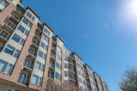 Austin, texas- Mid-rise apartment complex in a low angle view. Facade of an apartment building with picture windows and balconies with bicycles on some railings.の写真素材