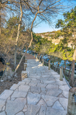 Austin, Texas- Stairs on a slope near Lake Austin with concrete pieces steps. Outdoor stairs with trees on the left and barrier with chains and logs on the right.の写真素材