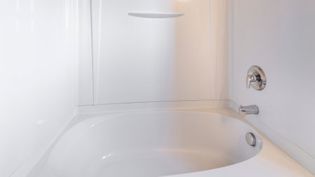Panorama Alcove tub-shower combo kit with wall mounted shower head and faucet. Bathroom interior with acrylic wall bathtub surround against the beige wall.の写真素材