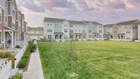 Panorama Puffy clouds at sunset Large lawn field in the middle of townhouse buildings. Residential...