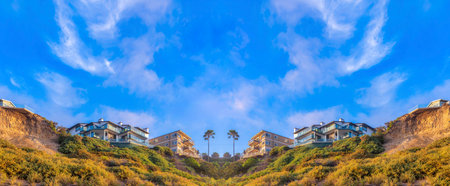 Abstract mirrored background Low angle view of a mountain slope with wild plants and buildings on...