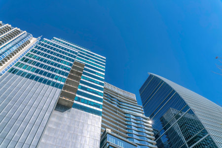 Looking up at modern glass buildings with windows that reflects the city views. Facade of...