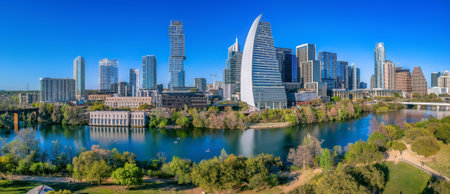 Colorado River at the front of Austin, Texas cityscape. There is a park at the front and a view of...