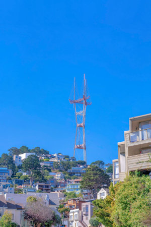 Peak of Sutro Tower above the hill with houses on the slope at San Francisco, California. Tower against the clear blue sky above the residential area.の写真素材