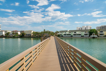 Boardwalk over the brackish water of a lake near the residential area at Destin, Florida. Pathway heading to the row of houses with balconies against the sky background.の写真素材