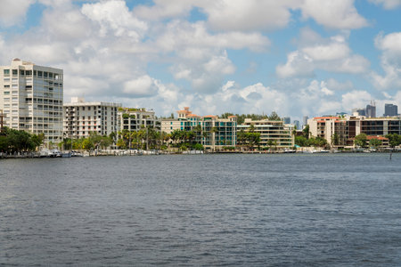 Modern residential buildings with oceanfront view at the bay in Miami, Florida. Views of the ocean with boats near the shore at the front of the buildings against the cloudy sky background.の写真素材