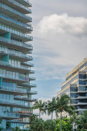 Two modern buildings with pastel sky background at Miami, Florida. There is a high-rise building on the left with glass railings at balconies across the building on the right with reflective glass.の写真素材
