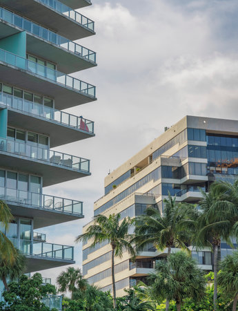 Condominium and corporate building against the sky background in Miami, FL. There is a condo on the left with glass railings across the office building with terrace and reflective glass on the right.の写真素材
