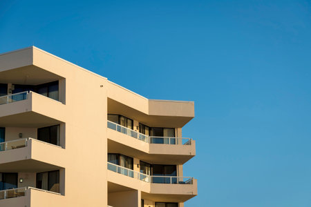 Building exterior with balconies at the corners against the blue sky in Destin, Florida. View of a building top with metal and glass railings at the balconies.の写真素材
