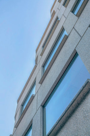 Modern building with windows that reflects blue sky viewed from below. Architecture of a commercial residential structure in San Francisco Califronia downtown.の写真素材