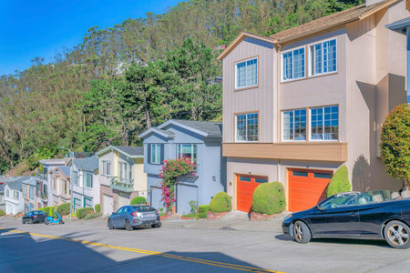 San Francisco California residential area with houses along a steep street. Neighborhood landscape on a sunny day with homes along an inclined road with parked vehicles.の写真素材