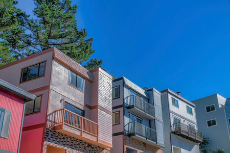 Houses on a sunny day in San Francisco residential area against blue sky. Facade of homes on a bright neighborhood in Califronia with flat roofs and balconies.の写真素材