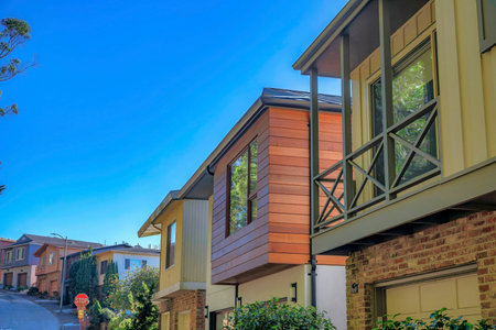 Beautiful homes along street road in a neighborhood in San Francisco California. Beautiful residential architecture with two-storey houses against clear blue sky.の写真素材