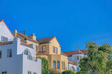 Houses and lush trees against blue sky in San Francisco California. The homes have balconies that overlooks a scenic residential landscape on a sunny day.の写真素材