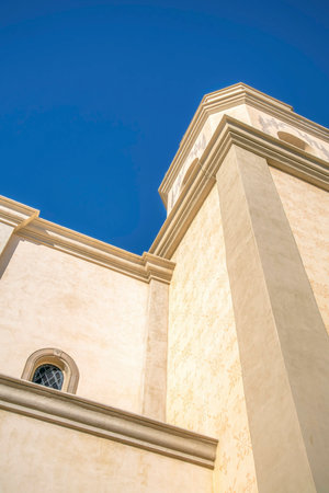 Building exterior with white stone wall against blue sky in Tucson Arizona. Architectural structures in the city with a building featuring arched windows viewed on a sunny day.の写真素材