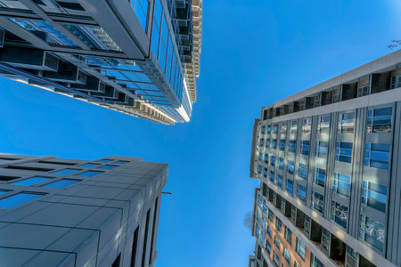 Modern apartments with sunlit exterior against vibrant blue sky on a sunny day. Looking up at modern residential buildings with windows reflecting the skyscpae in Austin Texas.の写真素材