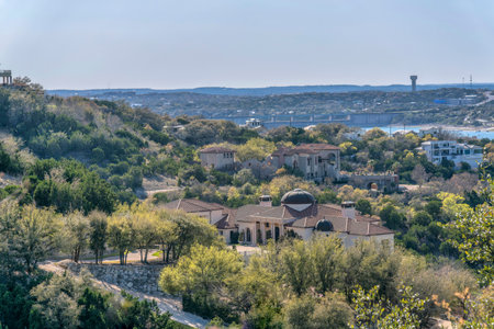 Buildings and trees in Austin Texas with Lake Austin and blue sky background. Scenic panorama of luxurious houses surrounded by lush trees along the water reservoir.の写真素材