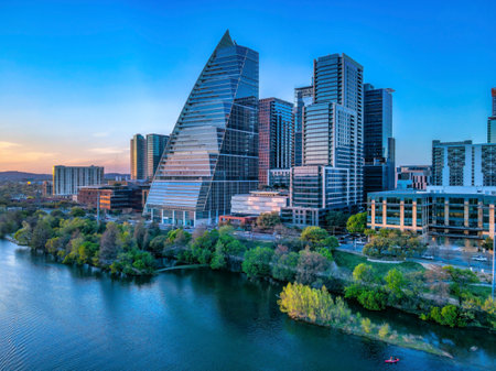 Colorado River near the modern corporate buildings at Austin, Texas. There is a river at the front beside the road near the buildings against the sunset sky horizon.の写真素材