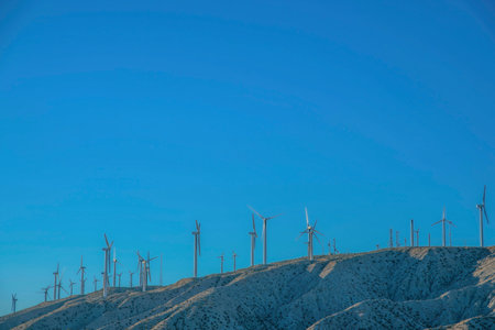 Windmill farm on top of a desert mountain in California. Wind turbines with different towers on a...