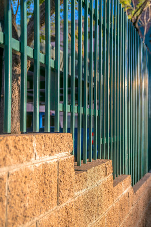 Close-up of a concrete block wall with painted green railings- Phoenix, Arizona. Selective focus of a fence wall with metal railings above the concrete blocks.の写真素材