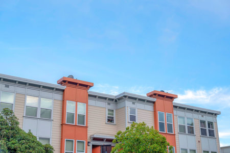 Apartment building with beige, gray, and orange exterior in San Francisco, California. Apartment exterior with single hung windows and beige vinyl lap wall claddings.の写真素材