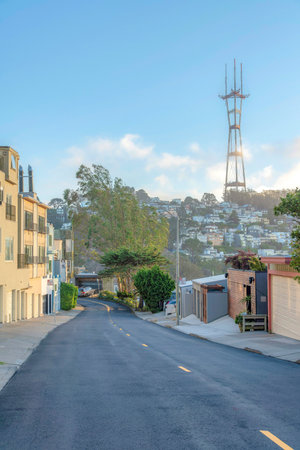 View of Sutro Tower from the road in the middle of residential buildings in San Francisco, CA. There...