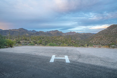 Helipad near the field of saguaro cactuses at Sabino Canyon State Park in Tucson, AZ. There is a view of mountain range against the cloudy sky from the helipad at the front.の写真素材