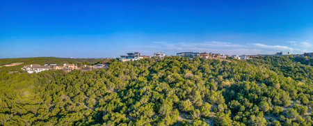 Austin, Texas- Rich residential area on top of a hill in panoramic view. Large residential buildings on top of a hill with trees on the slope against the clear blue sky background.の写真素材