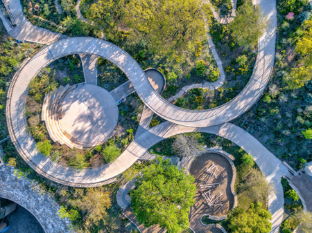 Empty park at Austin, Texas with spiral concrete pathway with small amphitheater in the middle. Aerial view of a park surrounded by plants and trees near the stone wall on the bottom left side.の写真素材