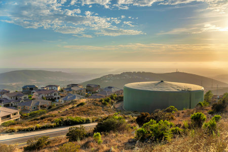Large water community conservation tank at San Marcos in San Diego, California. Water tank near the houses on the left against the view of mountains and sunset sky background.の写真素材