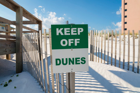 Destin, Florida- Keep Off Dunes sign on a fence panel with wood planks connected with steel wires. Close-up of a sign on a sand dunes near the small bridge on the left.の写真素材