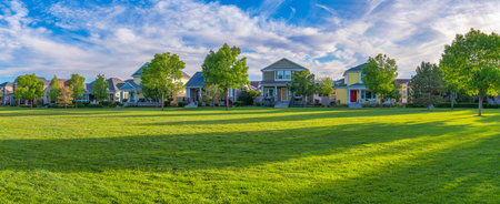 Residential area at Daybreak, Utah with large green fied at the front. There are facades of...