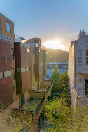 High angle view of multi-storey townhouses with a view of a mountain at the back against the sunset. Townhouses with balconies and wood claddings on the left across the house with wood lap siding.の写真素材