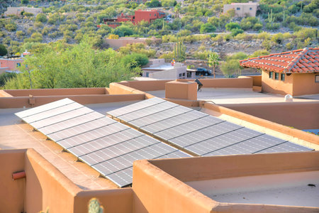 Solar panels on a flat roof of a mediterranean house at Tucson, Arizona. From the roof there is a view of a neighborhood with cactuses outdoors.の写真素材